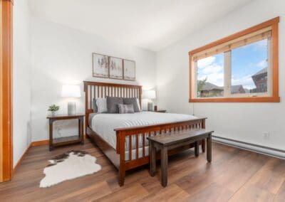 White walled bedroom with Wooden Bedframe, small rug and wooden floor